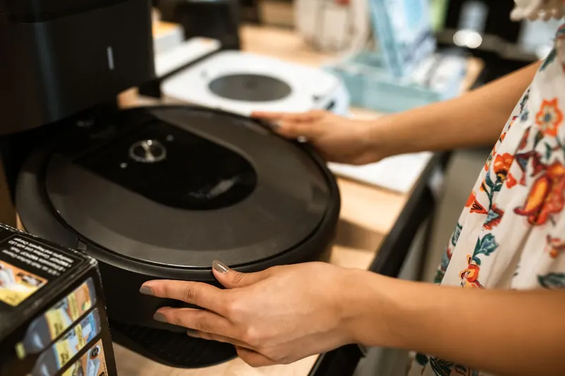 A customer examines a sleek robotic vacuum cleaner in a modern store