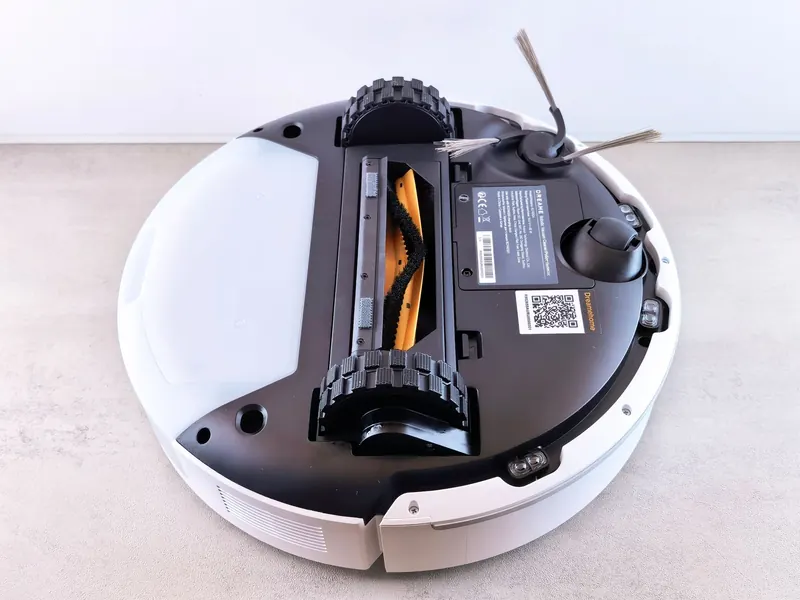 Close-up view of a robotic vacuum cleaner's underside displaying brushes and sensors