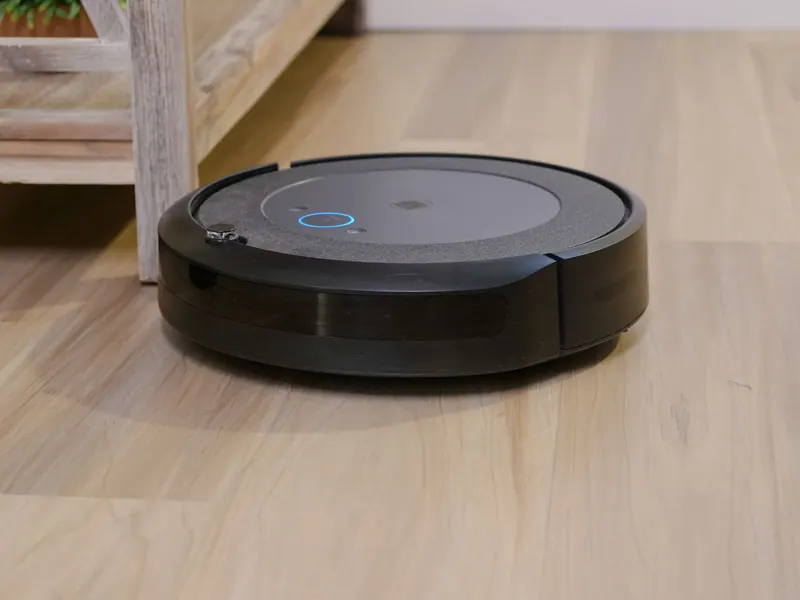 Autonomous vacuum cleaner navigating wooden floor indoors, showcasing smart home technology