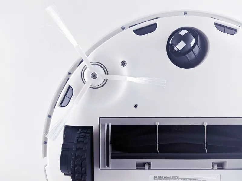 Close-up of a modern robotic vacuum cleaner underside showing brushes and components