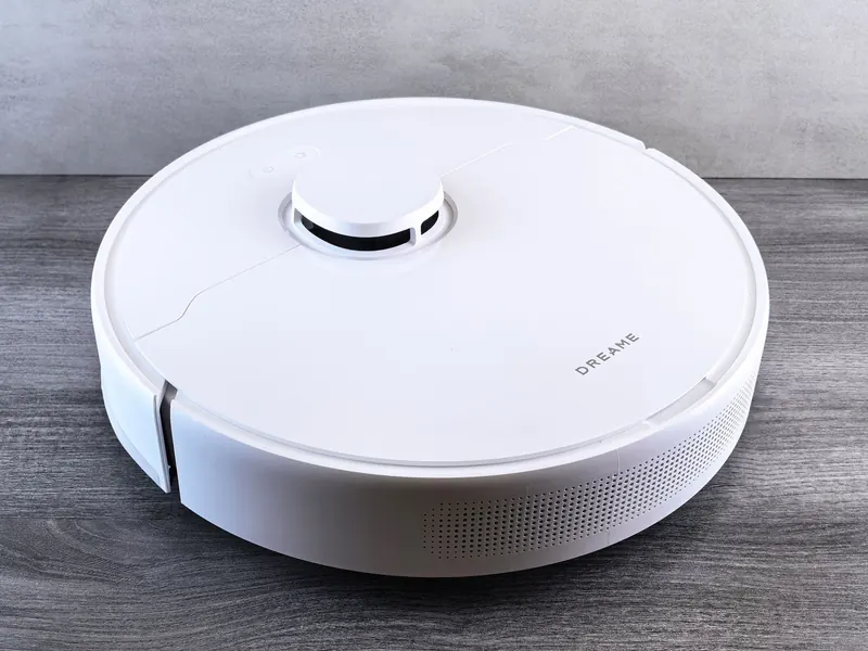 High-angle view of a sleek white robotic vacuum cleaner on a wooden floor, perfect for smart home setups